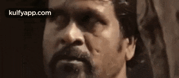 a close up of a man 's face with a beard and mustache looking at the camera .
