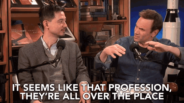 two men are sitting in front of microphones and the words it seems like that profession they 're all over the place