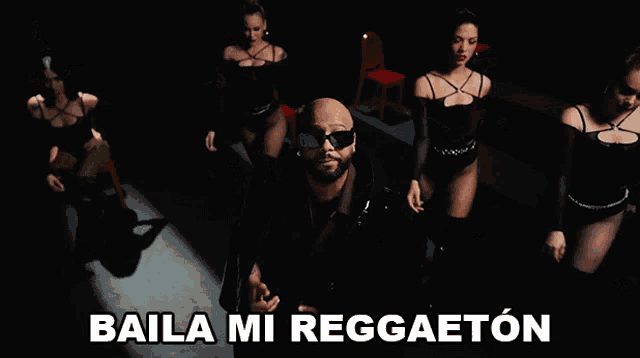 a man is standing in front of a group of women with the words baila mi reggaeton on the bottom right