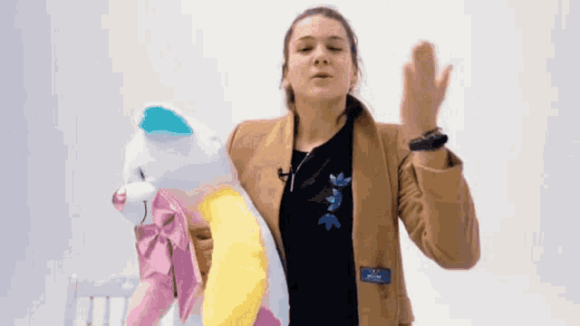 a woman in a brown jacket is holding a stuffed animal and giving a high five .