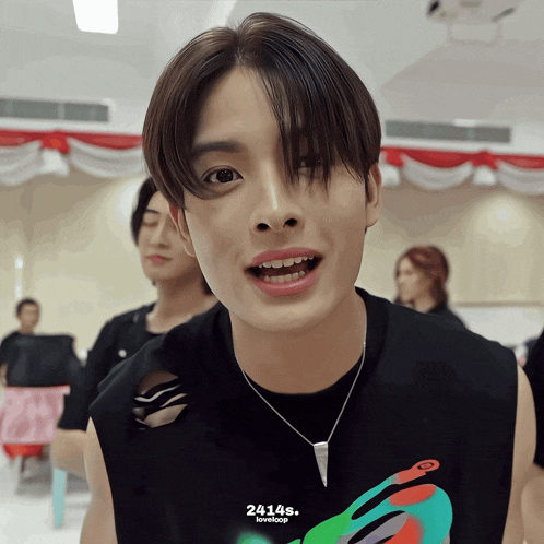 a young man wearing a black tank top and a necklace with the number 24145 on it
