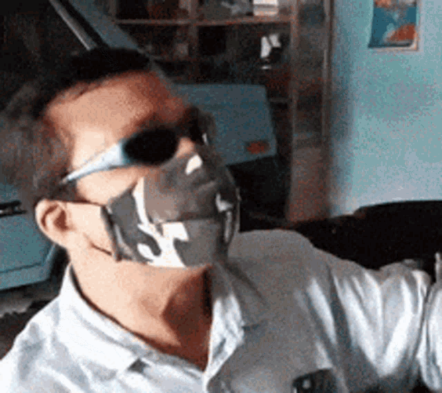 a man wearing a mask and sunglasses is sitting in front of a car