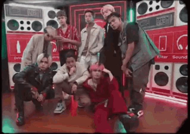 a group of young men are posing for a picture in front of a row of speakers .