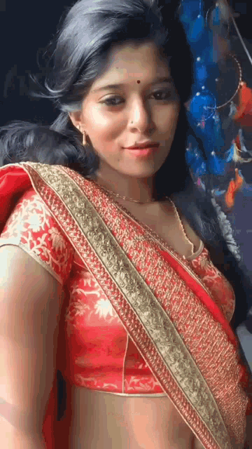 a woman is wearing a red blouse and a gold necklace .