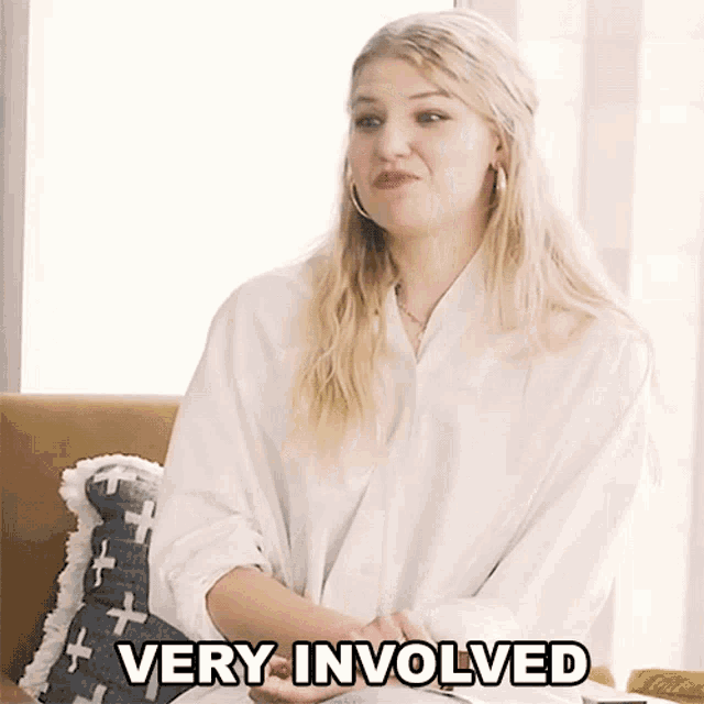 a woman in a white shirt is sitting on a couch with the words very involved written below her