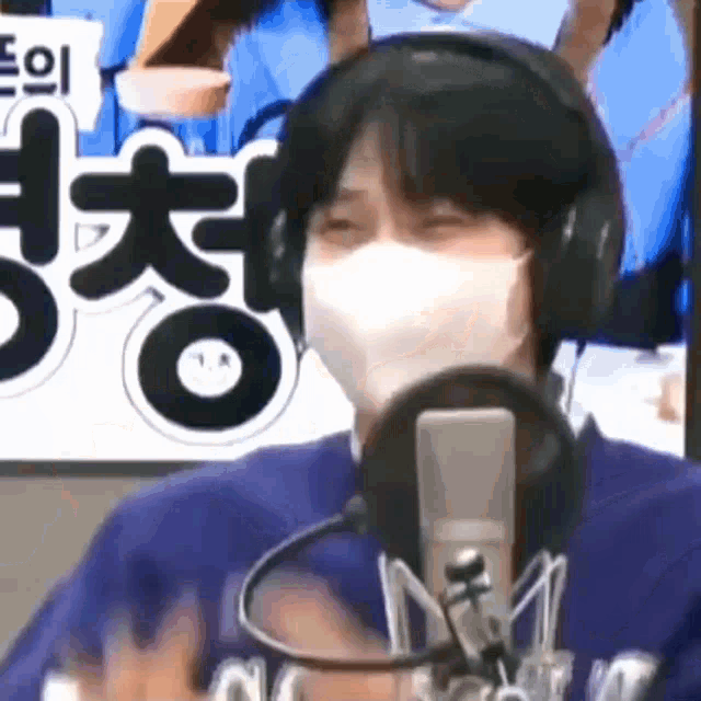 a man wearing a face mask and headphones is talking into a microphone .