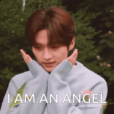 a young man in a blue sweater is making a face and says `` i am an angel ''