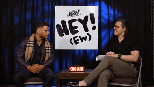 two men sitting in front of a sign that says hey ( ew )
