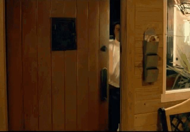 a man in a white shirt stands in front of a door