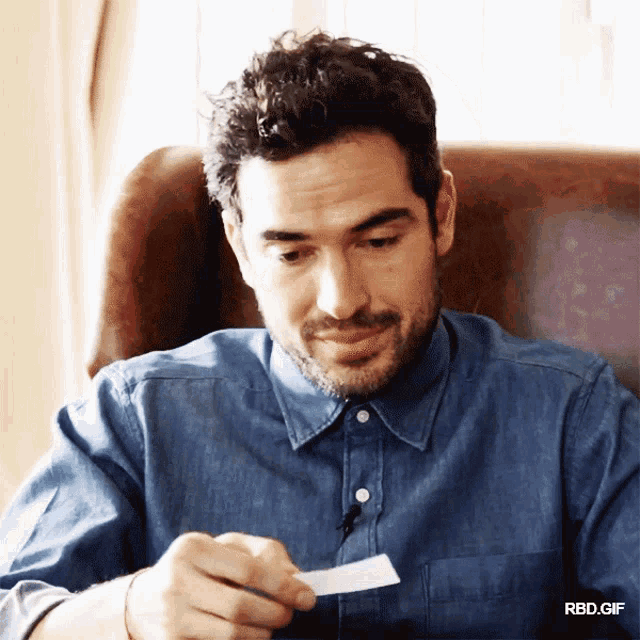 a man in a blue shirt is holding a piece of paper in his hand