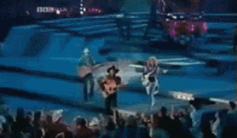 a man in a cowboy hat is playing a guitar on a stage in front of a crowd