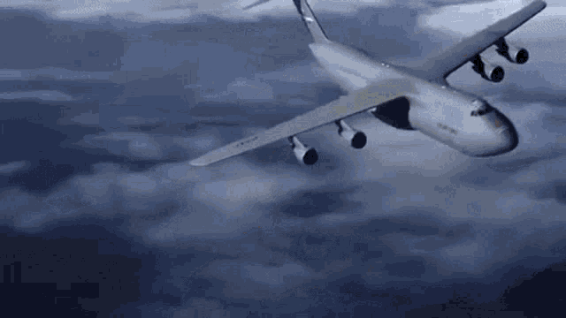 a large cargo plane is flying through the clouds .