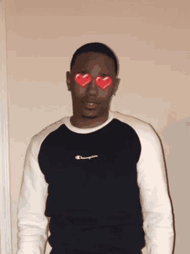 a man wearing a black and white champion sweater has hearts in his eyes