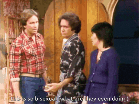 a man in a plaid shirt is talking to two other men and a woman in a blue dress