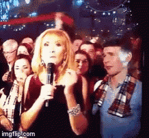 a woman is holding a microphone in front of a crowd with imgflip.com at the bottom of the screen