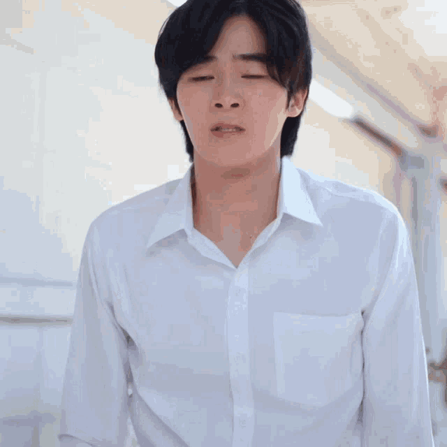 a young man in a white shirt is making a funny face