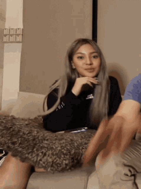 a woman is sitting on a couch wearing a black adidas sweatshirt