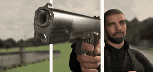 a man with a beard is holding a gun in his hand .
