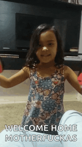 a little girl is standing in front of a television with her arms outstretched and says welcome home motherfuckas