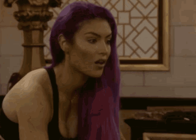a woman with purple hair and a black tank top looks surprised