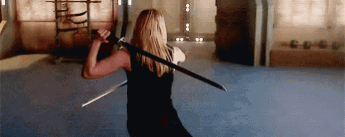 a woman in a black dress is holding two swords behind her back .