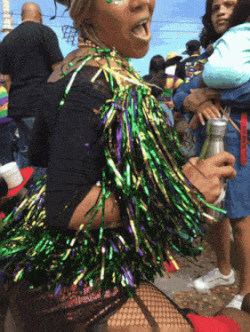 a woman wearing a mardi gras costume holds a can of soda