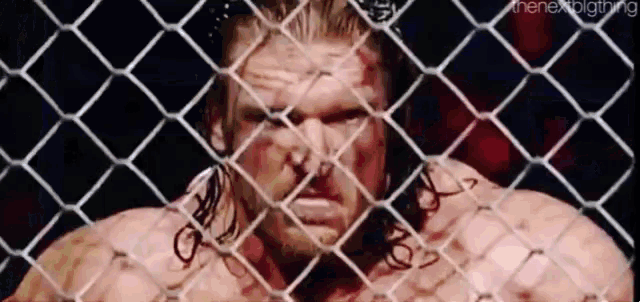 a man is standing behind a chain link fence looking at the camera .