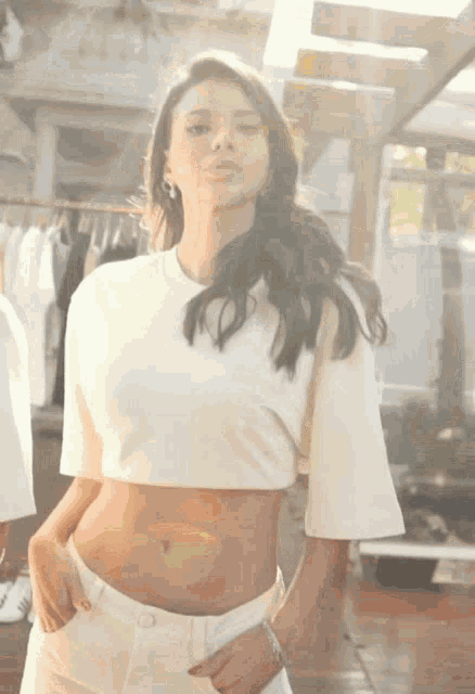 a woman wearing a white crop top and white shorts