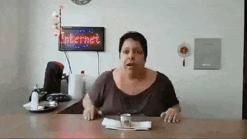 a woman is sitting at a desk in front of a sign that says internet .