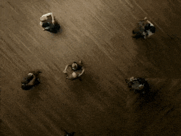 a group of people sit in a circle on a wooden floor