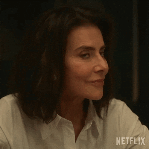 a woman in a white shirt is smiling and looking at something .
