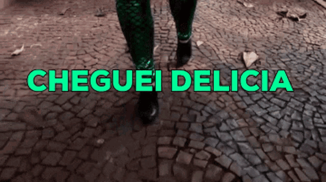 a person walking on a cobblestone street with the words cheguei delicia written in green