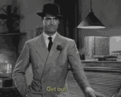 a man in a suit and hat says get out in a black and white photo
