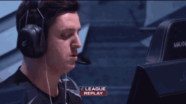 a man wearing headphones sits in front of a computer screen with the words league replay on it