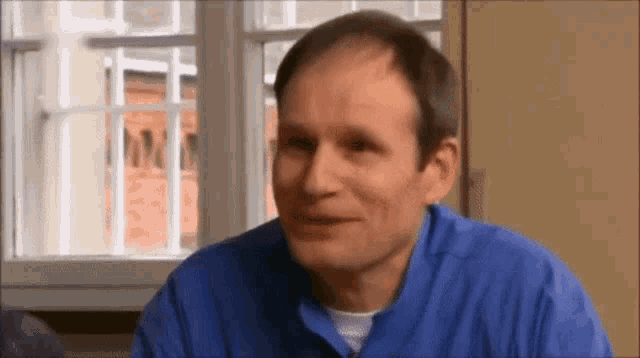 a man in a blue shirt is smiling and looking at the camera