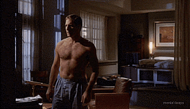 a man without a shirt is standing in a living room with the words mental troops on the bottom right