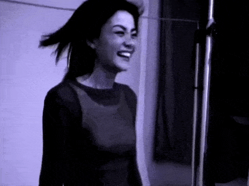 a woman in a black shirt is smiling in a black and white photo