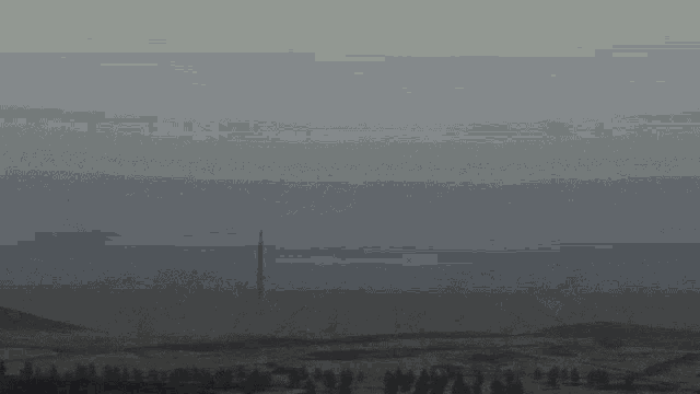 a light beam is coming out of a tower in the fog .