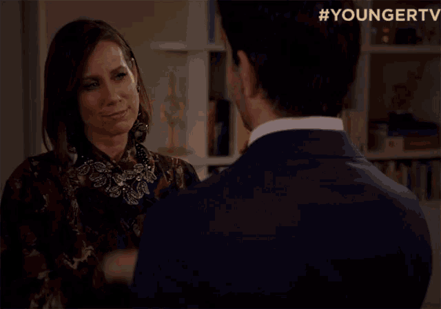a man and a woman are kissing in front of a bookshelf with the hashtag youngertv