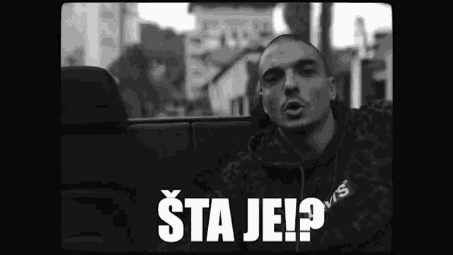 a black and white photo of a man in a car with the words sta je