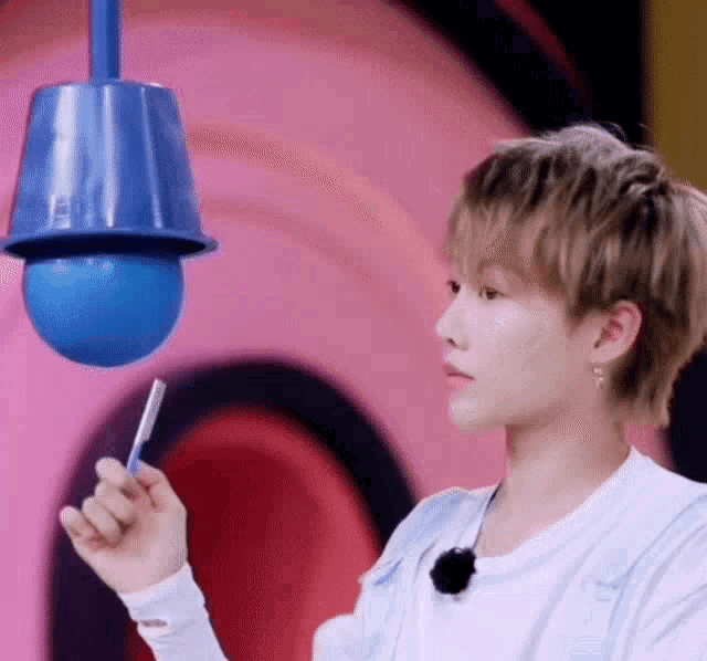a young man is holding a pencil in his hand in front of a blue ball .
