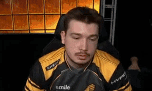 a man in a yellow and black jersey is sitting in a chair .
