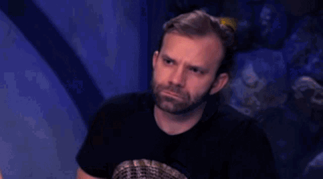 a man with a beard is making a funny face while holding his arm out .