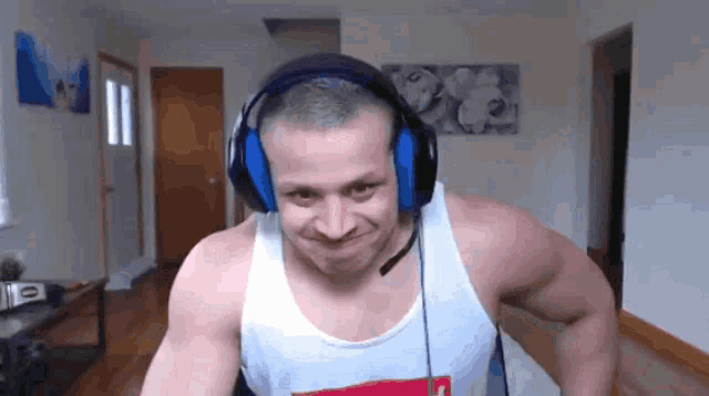a man wearing headphones and a white tank top is making a face