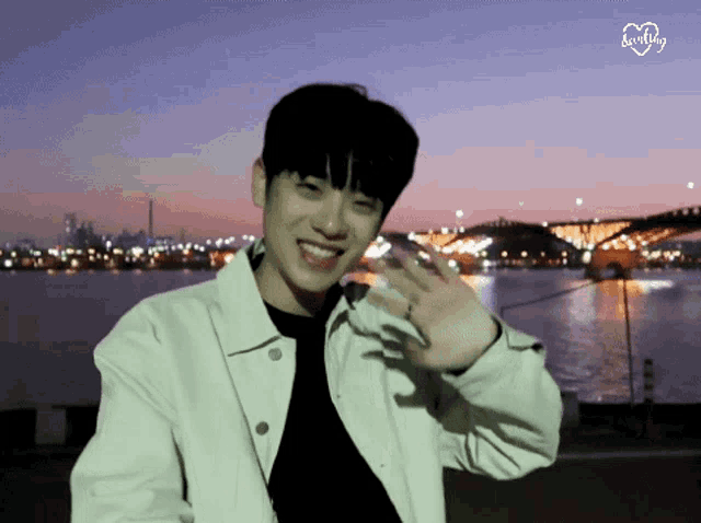 a young man waving in front of a body of water