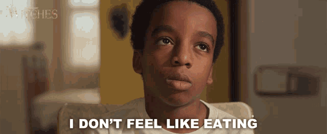 a young boy sitting in a chair with the words i don 't feel like eating below him