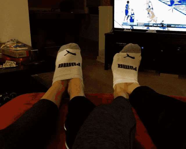 a pair of feet wearing puma socks are laying on a bed