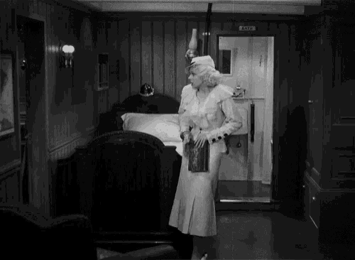 a black and white photo of a man and woman in a room with a sign that says ' captain ' on it