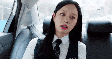 a woman in a school uniform is sitting in the back seat of a car .