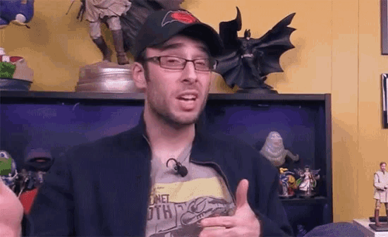 a man wearing glasses and a hat giving a thumbs up
